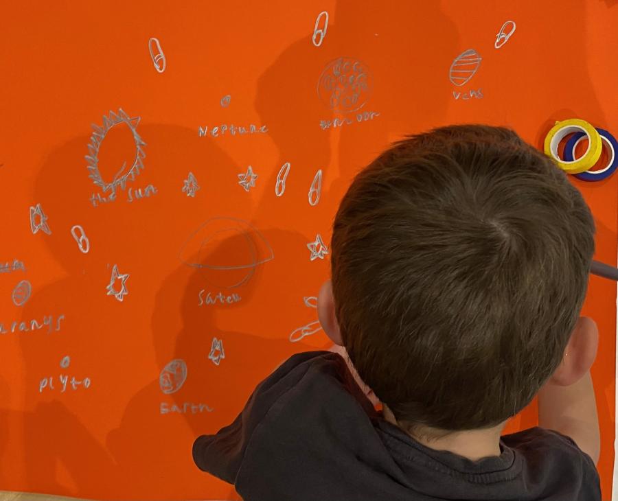 Back of child's head bent over drawing on orange background
