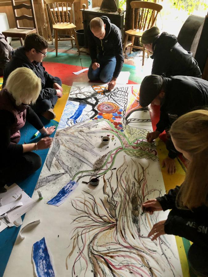 A group of people creating artwork on the floor of a cabin